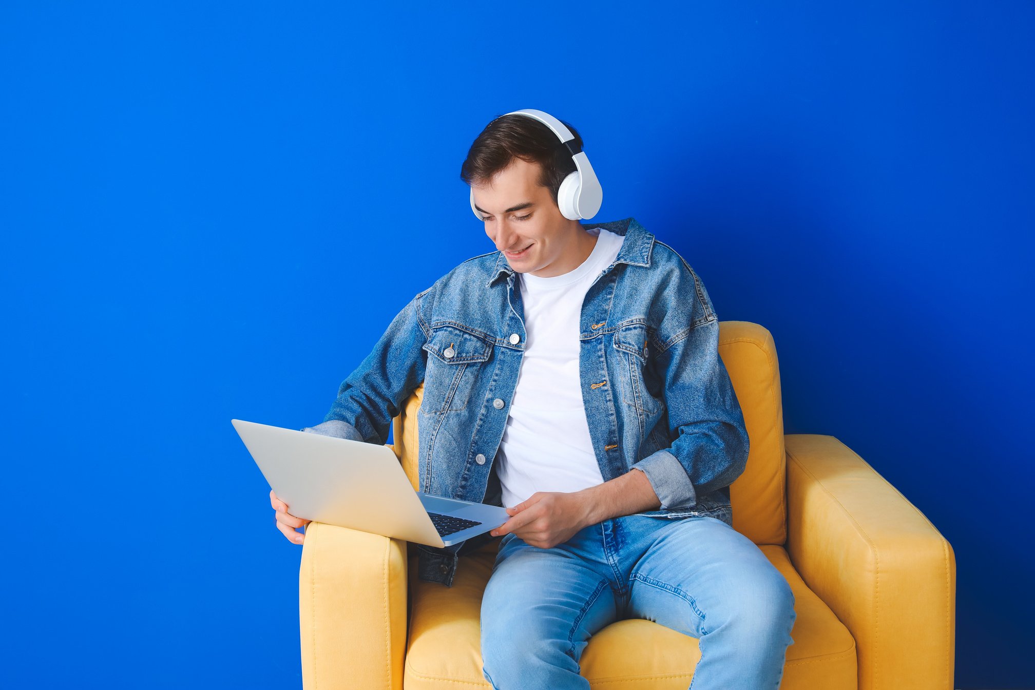 Male Student with Laptop Studying Online on Color Background